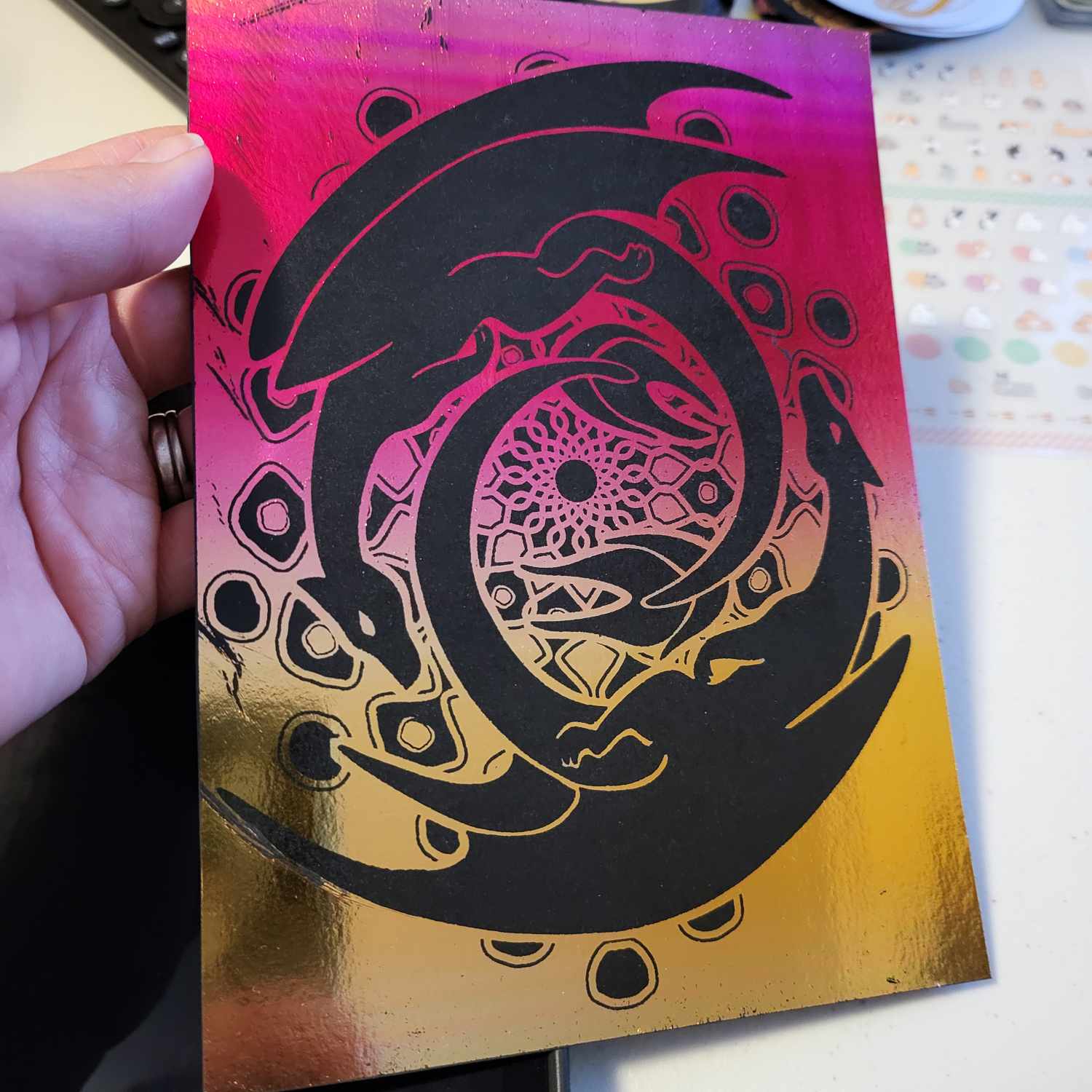 A reverse foil design on black card. The design is left as the black card and the background is completely foiled with a red to gold gradient foil.