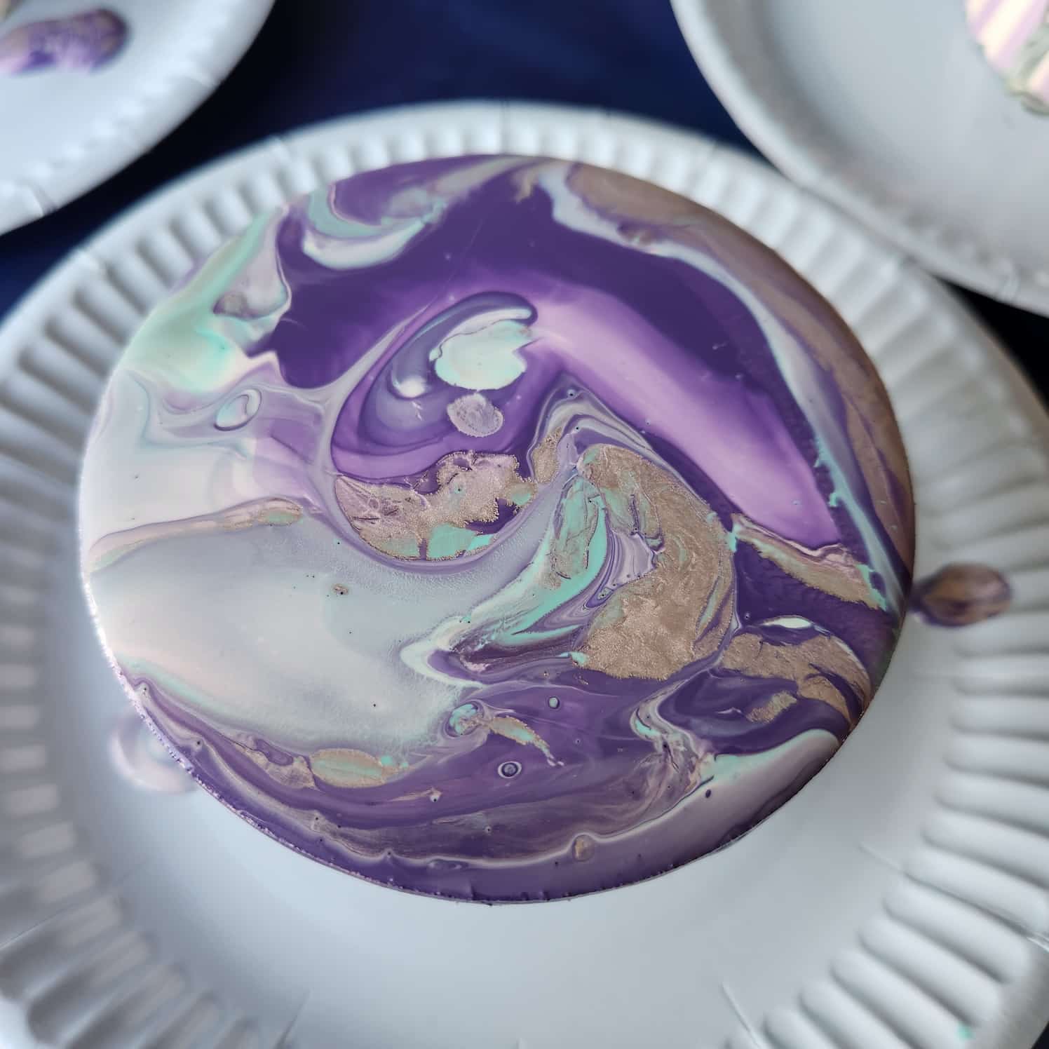 Coaster with a marbled purple, white, turquoise and gold design.