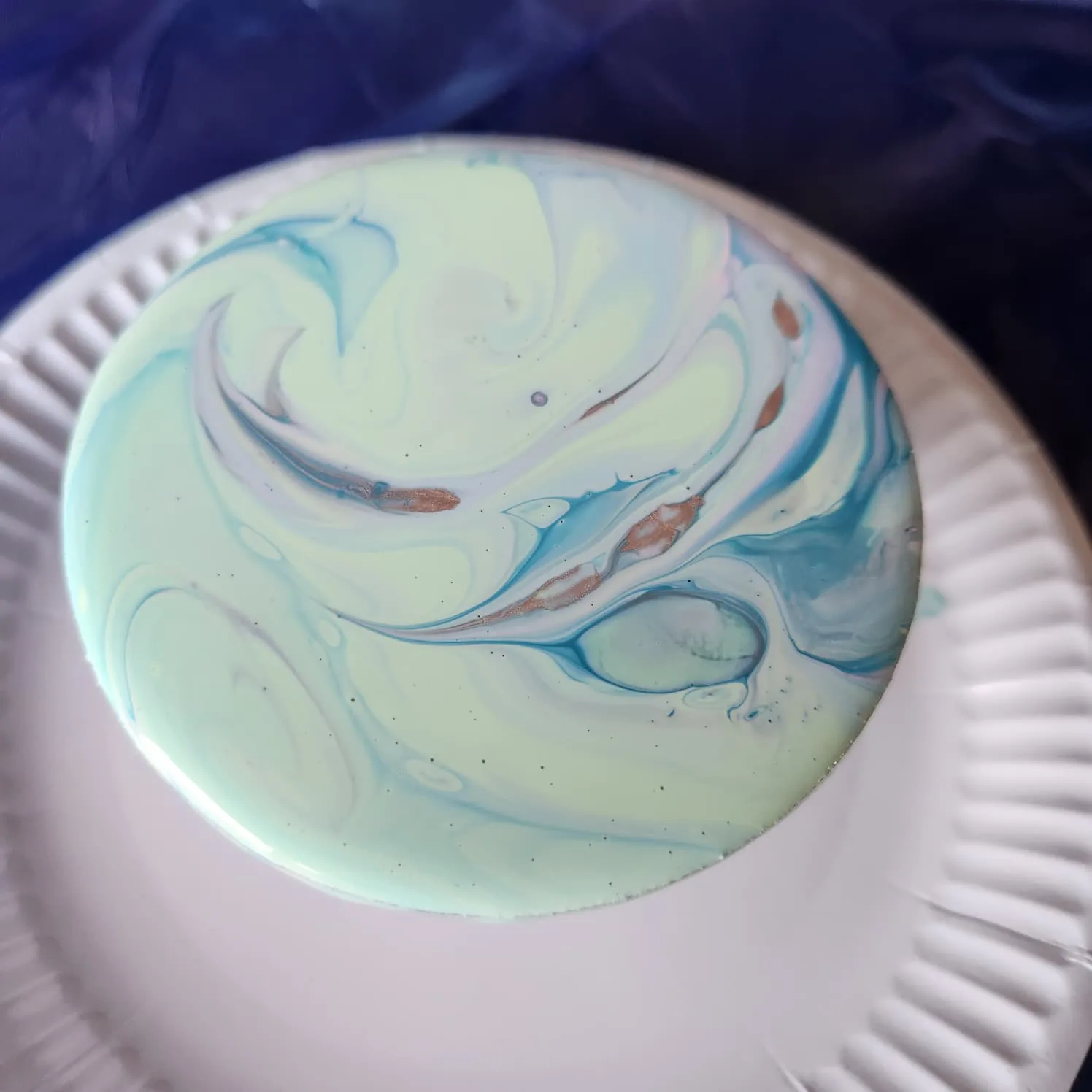 Coaster with a light mint, blue and gold design.