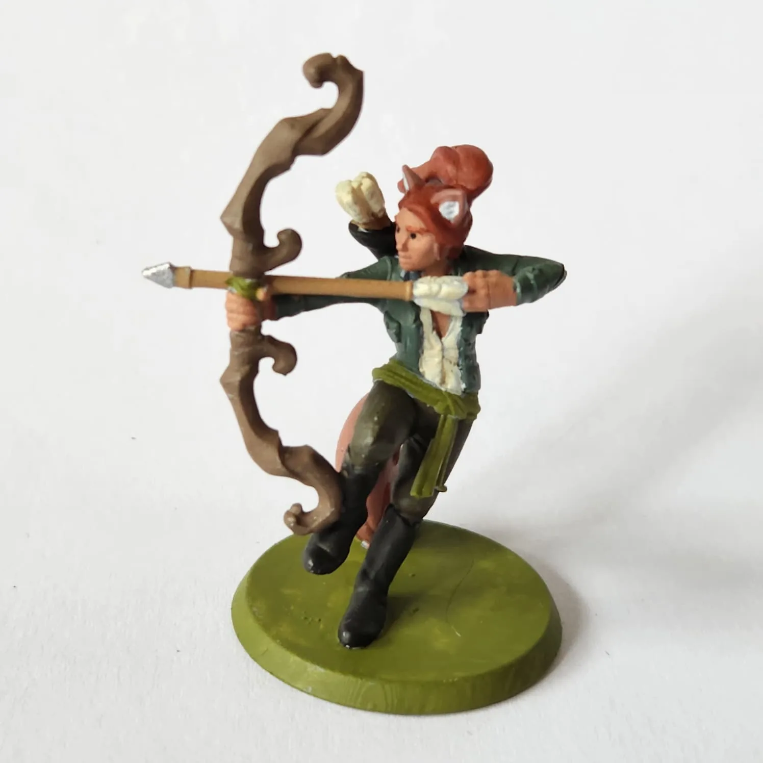 Minitature of female wildhunt ranger with fox-like ears and tail, but otherwise human appearance. She is posed in an action shot, balanced on one leg and her tail, aiming her bow off to the left. Her quiver shows over her right shoulder. She has black boots, green pants, green jacket and white shirt. Around her waist is a lighter green sash belt.