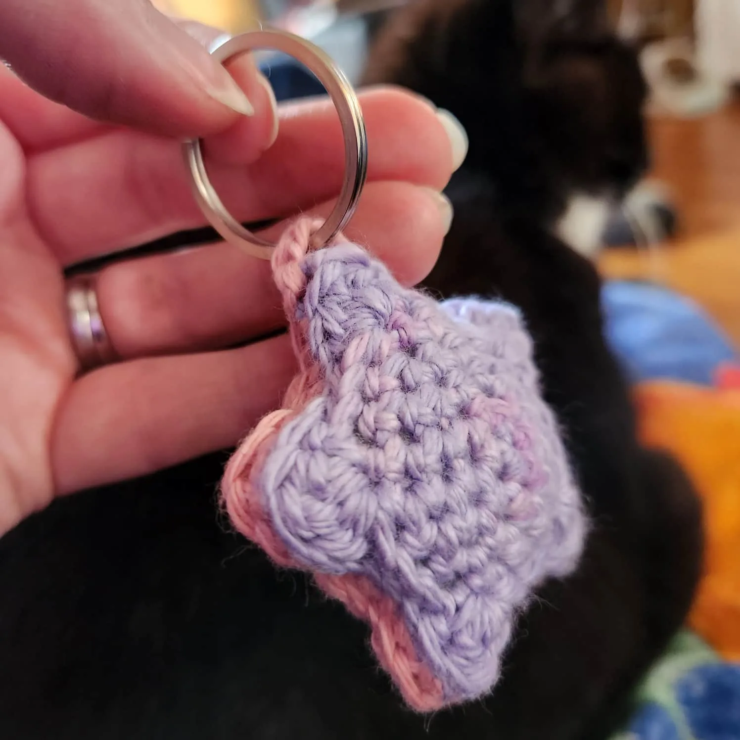 A pink and purple crochet star on a keyring hand in a hand.