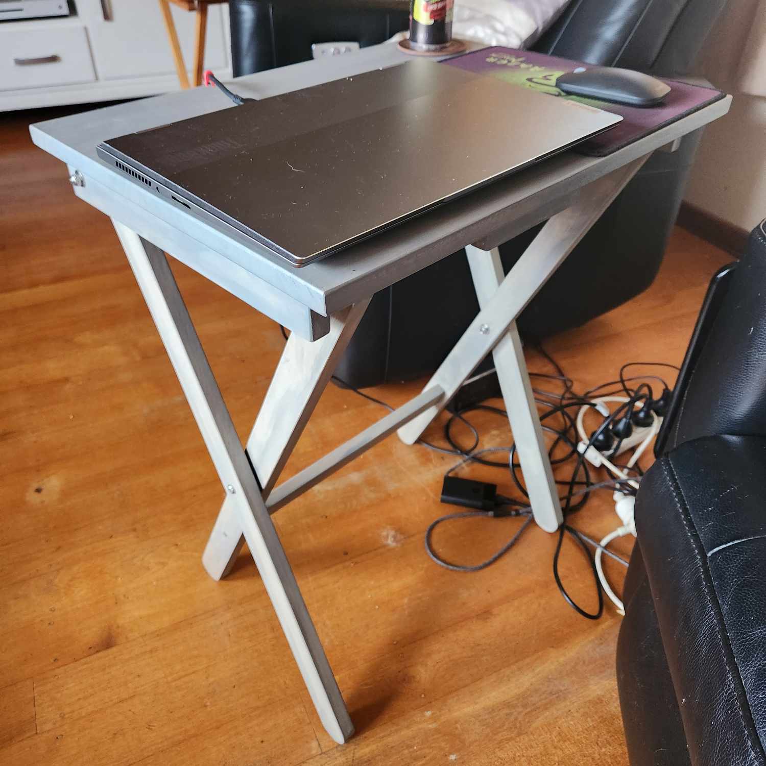The completed folding table, stained grey, with a laptop, mousepad, mouse, and drink on it.