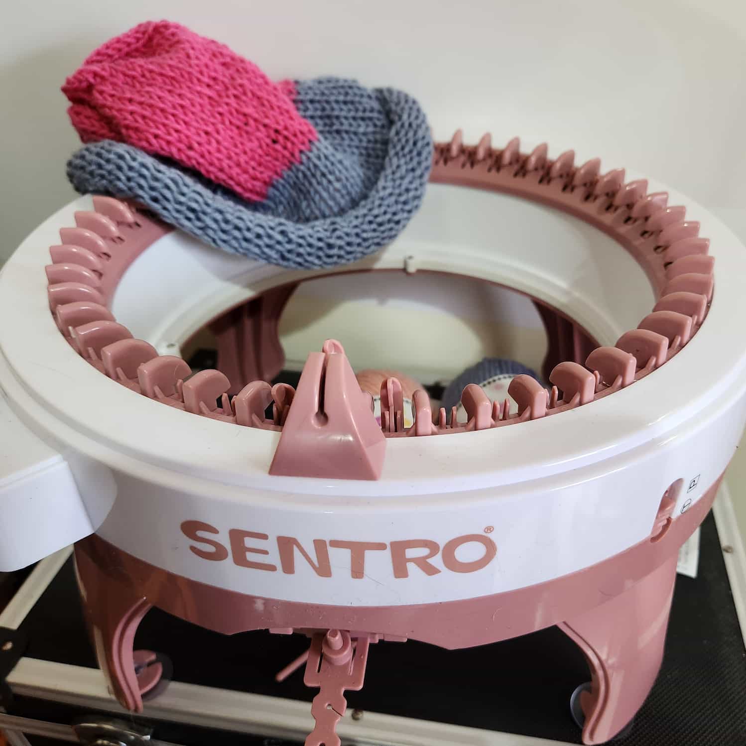 Large Sentro circular kitting machine. There is no yarn loaded, but a completed grey and pink beanie is draped over one side.