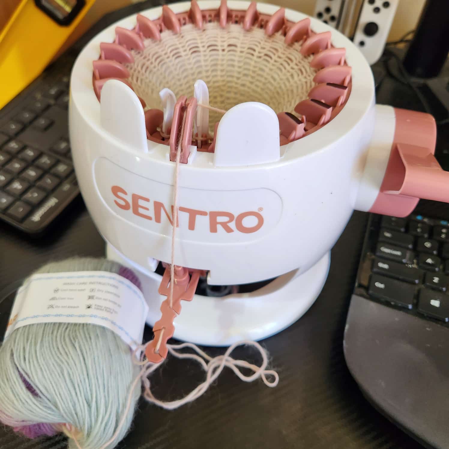 Small Sentro circular knitting machine. There is yarn attached and some knitting in progress.