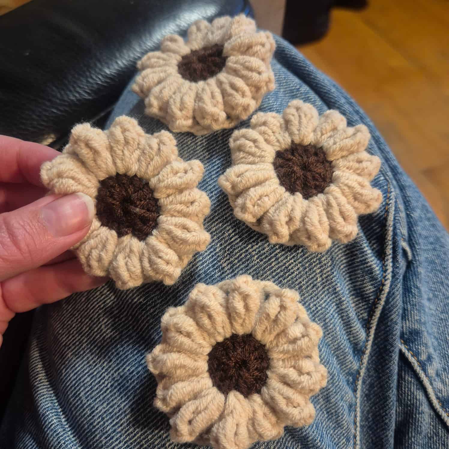 Four completed crochet flowers with cream petals and brown centers.