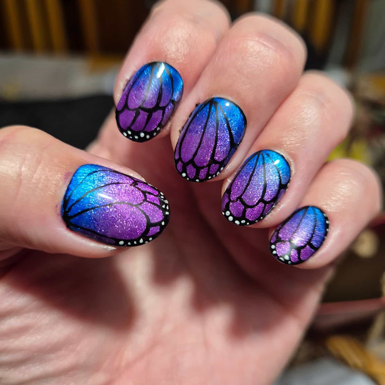 Shimmery, glittery blue to purple gradient butterfly nail design.