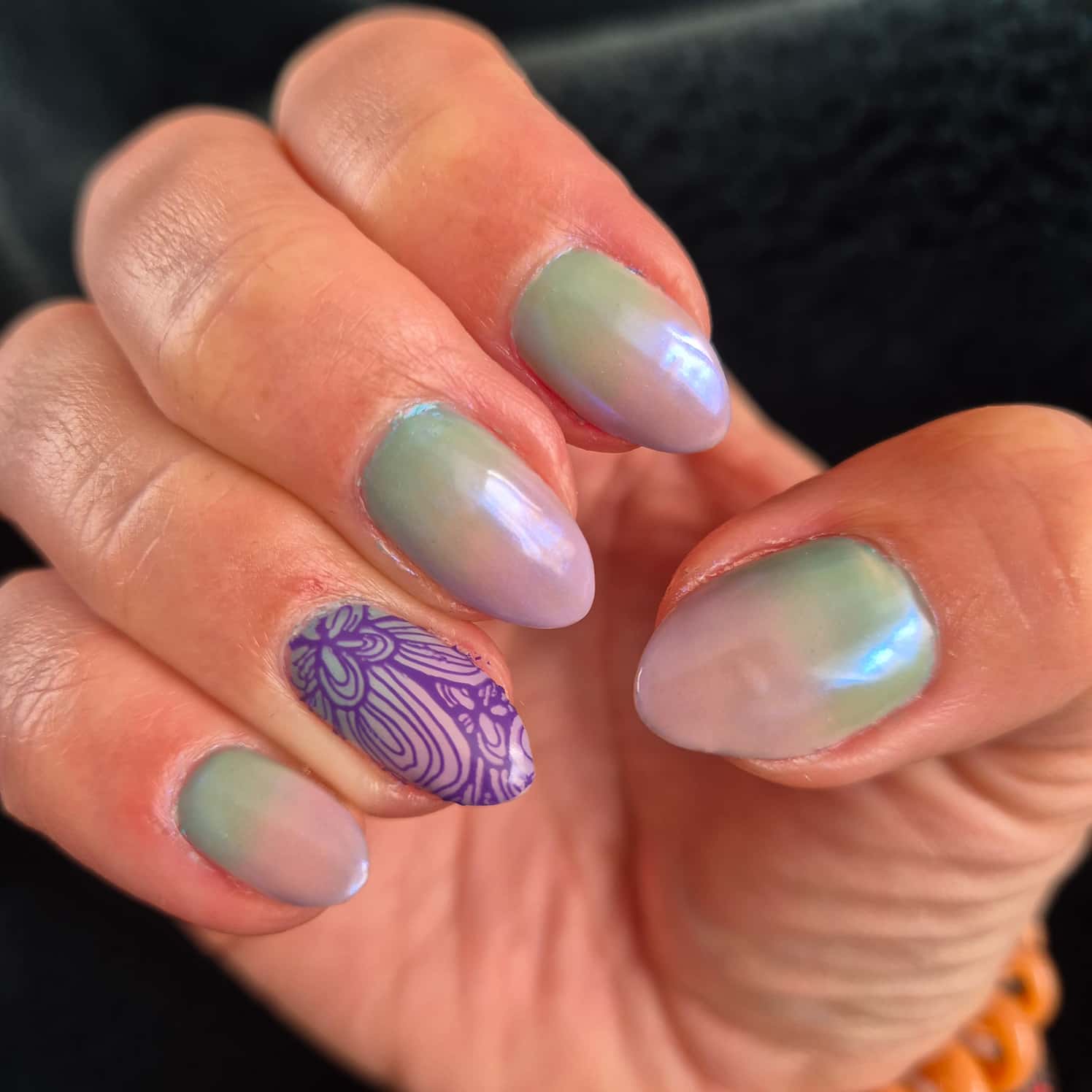 Pearly gradient nail design, green to pink. One nail is stamped with a purple floral design.