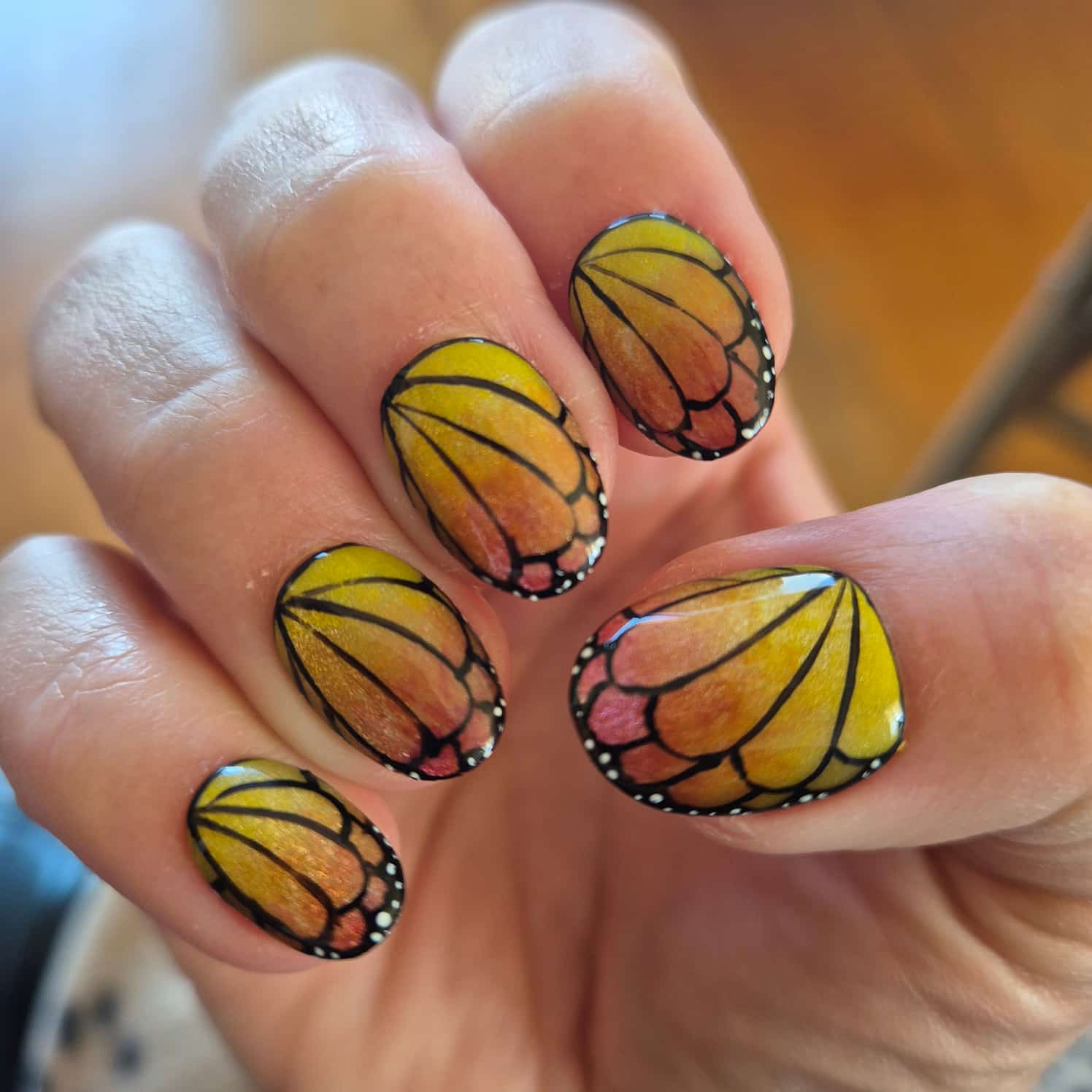Shimmery yellow to orange gradient butterfly nail design.