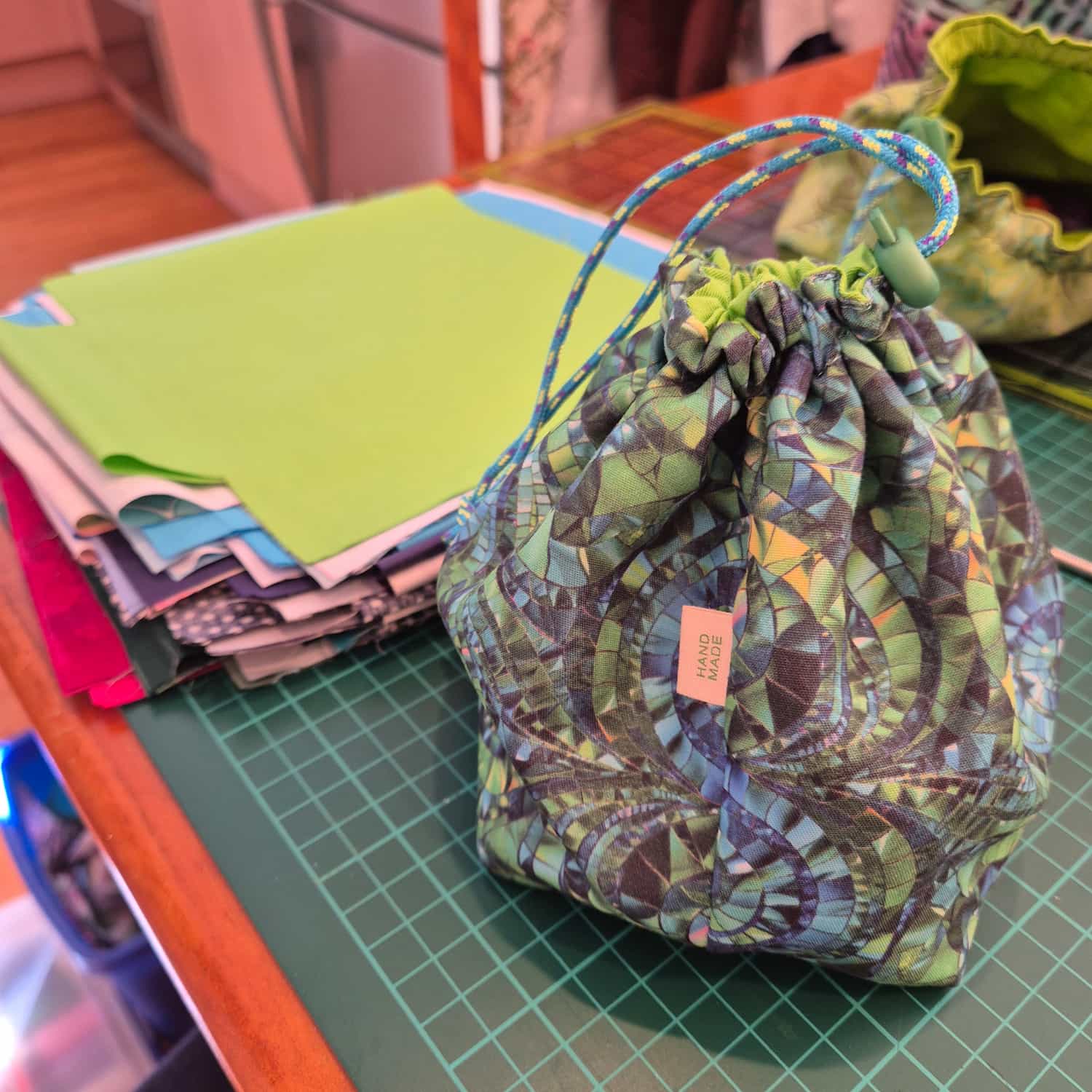 A dice bag in green and blue stained-glass effect fabric sitting on a green